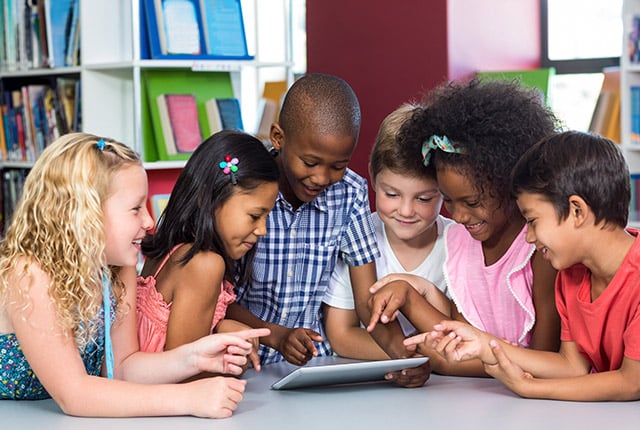 Mixed race children using digital table in library