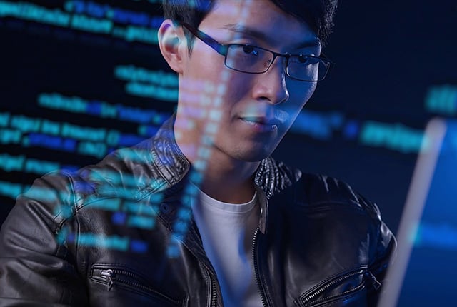 Asian man using computer with futuristic computer cybersecurity code preview
