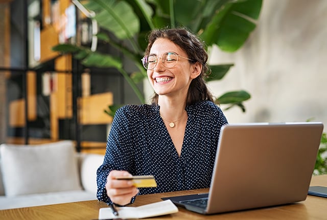 Happy woman with laptop using credit card