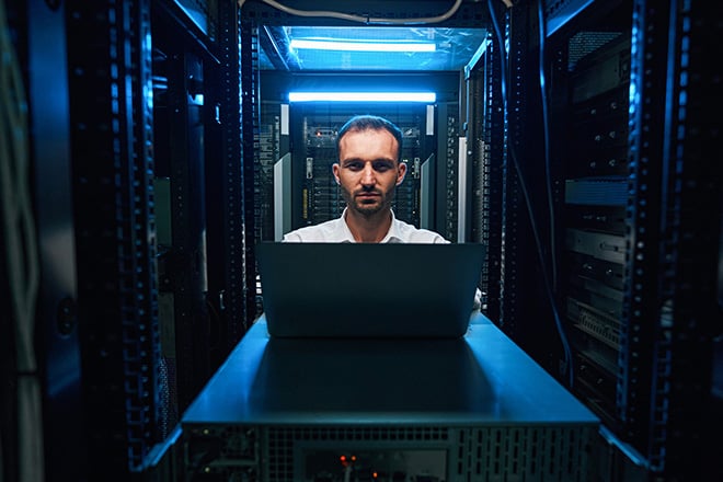 Man in server room behind laptop