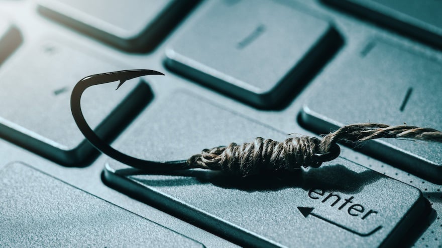 phishing and cyber crime concept. fishing hook on computer keyboard